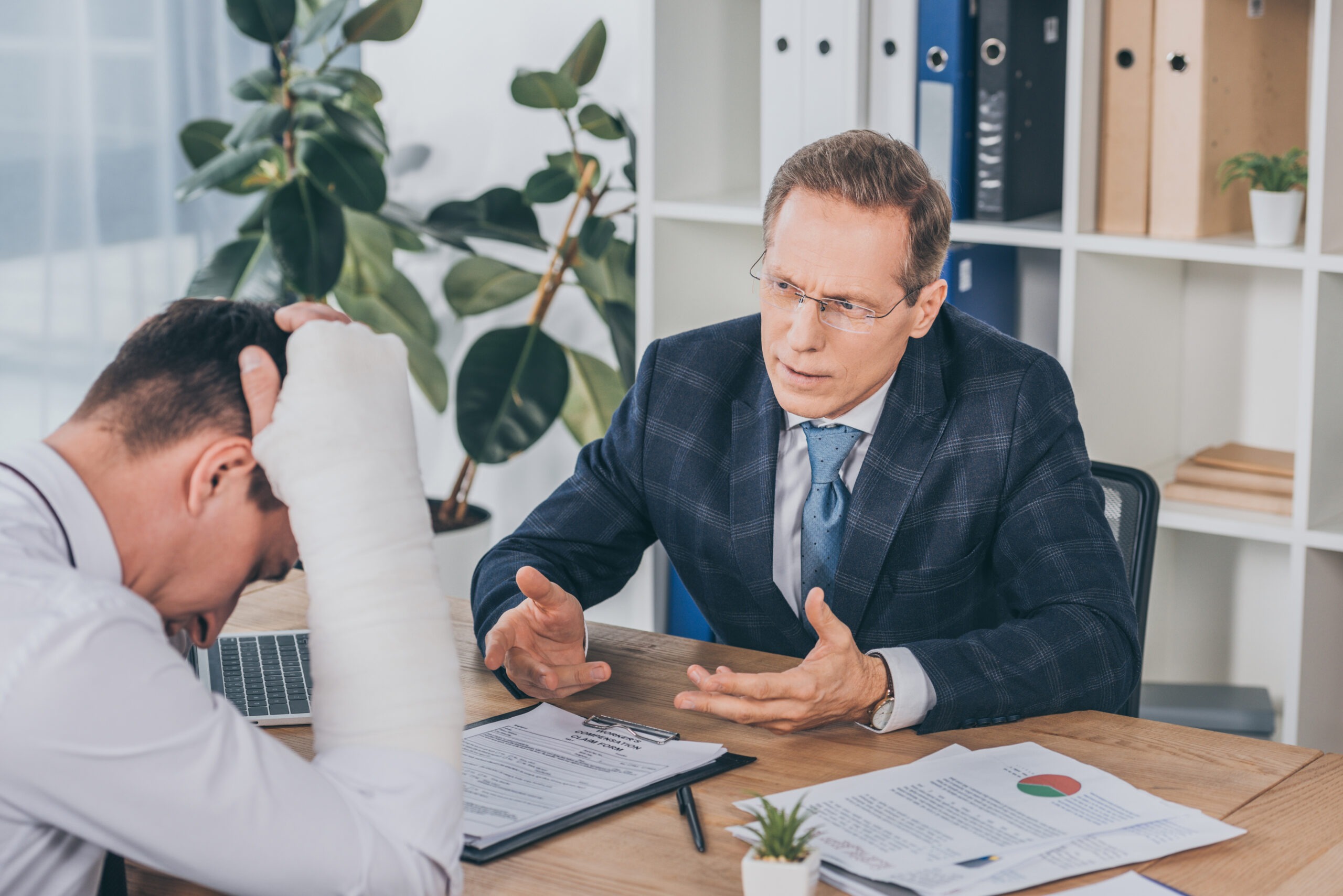 Injured worker with a broken arm reviewing workers' compensation claim documents with a representative